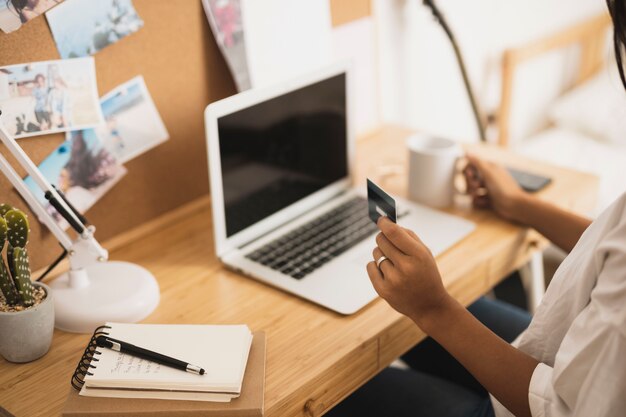 Mains tenant une carte de crédit et une tasse de café