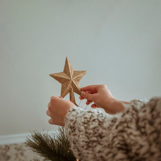 Mains tenant une étoile dorée pour l&#39;arbre de Noël