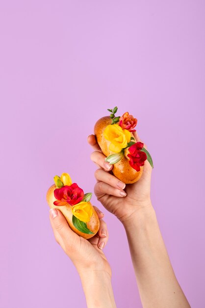 Mains tenant des hot-dogs écologiques avec des fleurs