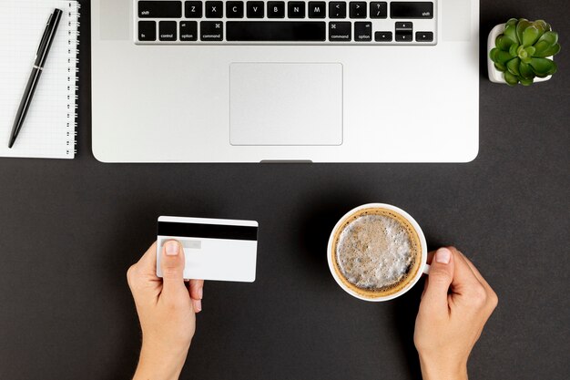 Mains tenant une tasse de café et une carte de crédit