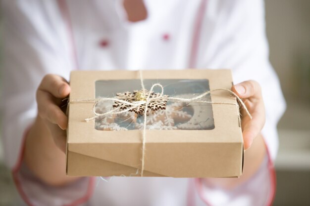 Mains tendant une boîte avec une collection de biscuits de noel