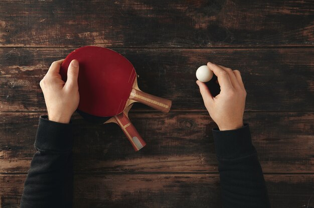 Les mains tiennent deux fusées de ping-pong professionnelles, attaque plus et défense