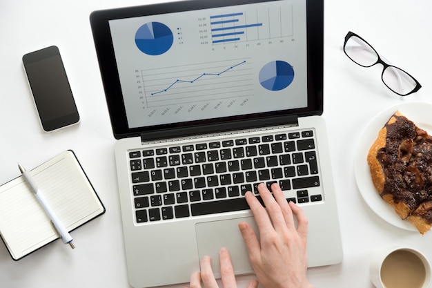 Mains travaillant sur un ordinateur portable avec un diagramme sur celui-ci