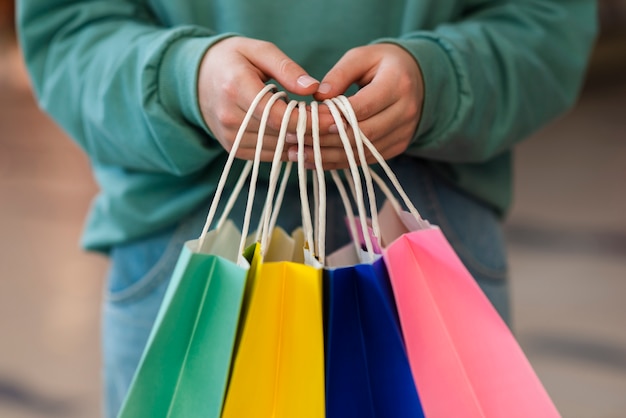 Mains de vue de face tenant des sacs en papier colorés