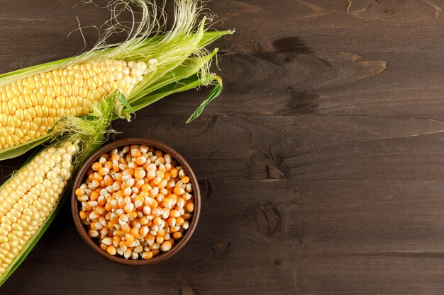 Maïs et céréales dans une assiette d'argile sur une table en bois foncé. vue de dessus.