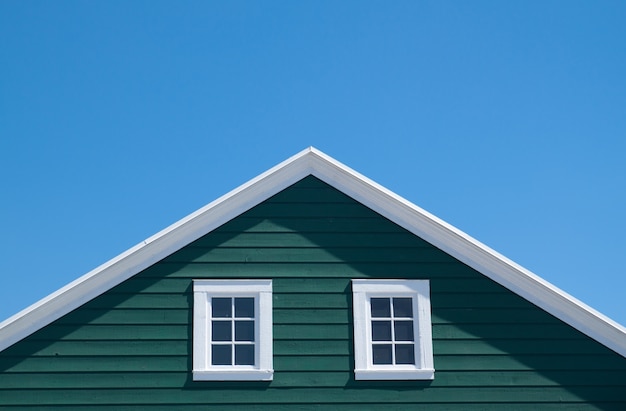 Maison verte et toit blanc avec ciel bleu en journée ensoleillée