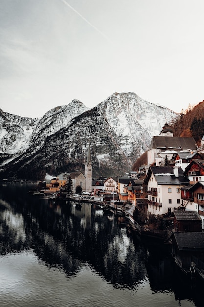 Photo gratuite maisons en béton brun et blanc près du plan d'eau et de la montagne