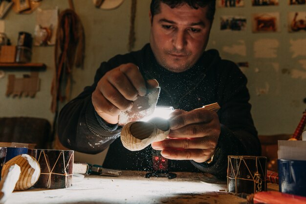 Maître sculptant des pièces de bois sous la lumière dans l'atelier