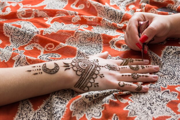 Maître tatouant mehndi peindre sur une main de femme