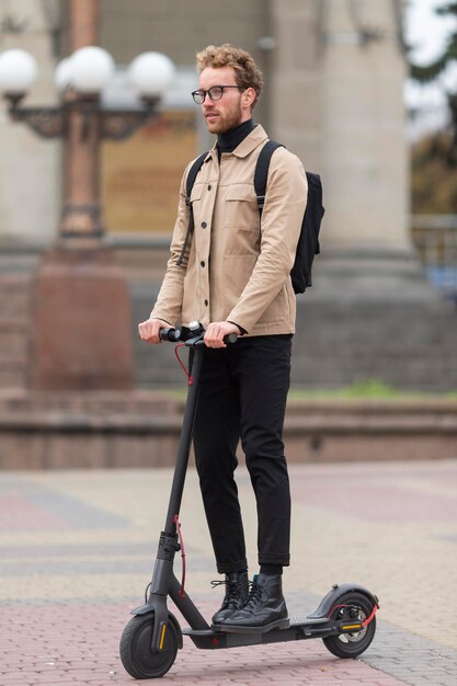 Mâle adulte posant avec un scooter électrique