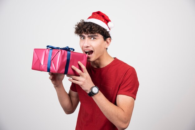 Mâle bouclé en bonnet de Noel posant avec boîte-cadeau.