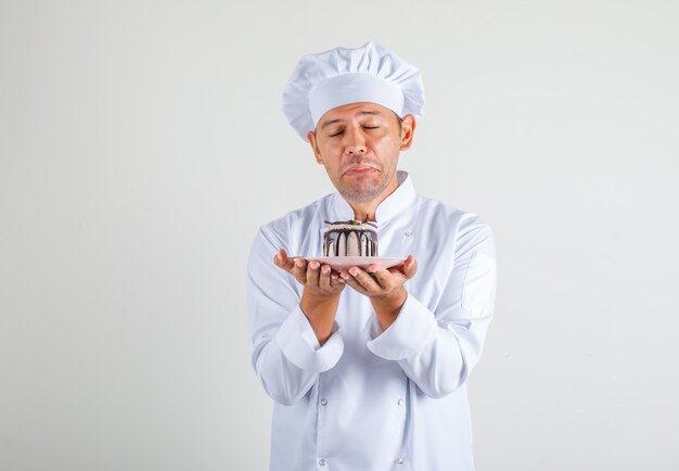 Mâle Chef Cuisinier En Uniforme Et Chapeau Tenant Le Gâteau Avec Les Yeux Fermés