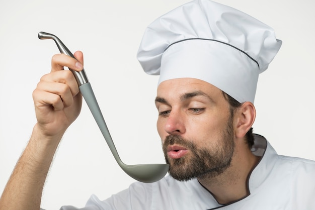 Photo gratuite mâle chef dégustation de soupe avec louche sur fond blanc