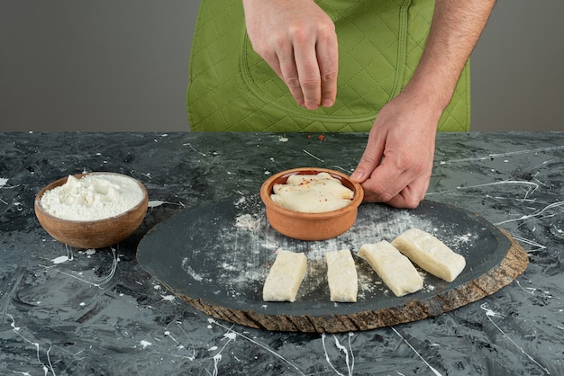 Mâle main ajoutant du sel à la pâte sur une table en marbre.
