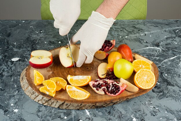 Mâle main coupant des pommes rouges fraîches sur table en marbre.