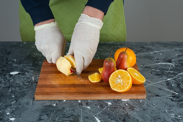 Mâle main coupe apple avec couteau sur le dessus de la planche de bois sur la table.