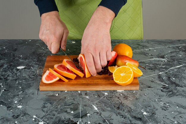 Mâle main dans des gants coupe pamplemousse juteux sur table en marbre.