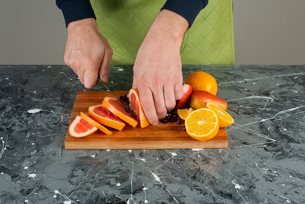 Mâle main dans des gants coupe pamplemousse juteux sur table en marbre.