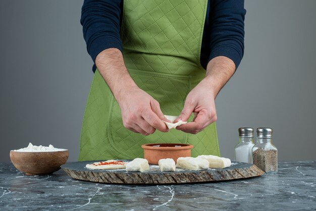 Mâle main dans des gants faisant de la nourriture sur une table en marbre.