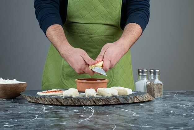 Mâle main dans des gants faisant de la pâte sur une table en marbre.