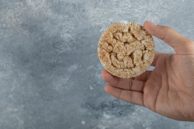 Mâle main tenant le gâteau de riz sur la surface en marbre