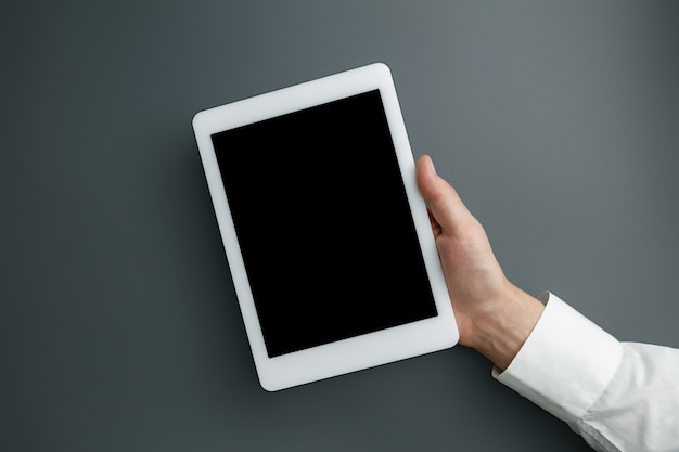 Mâle main tenant la tablette avec écran vide sur gris