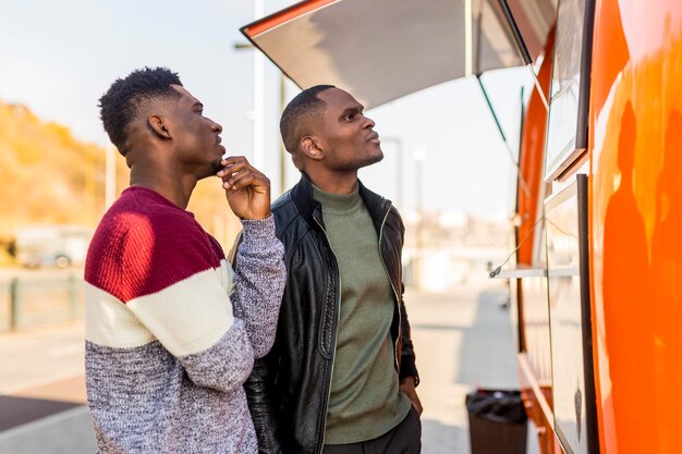 Males de tir moyen lisant le menu de camion de nourriture