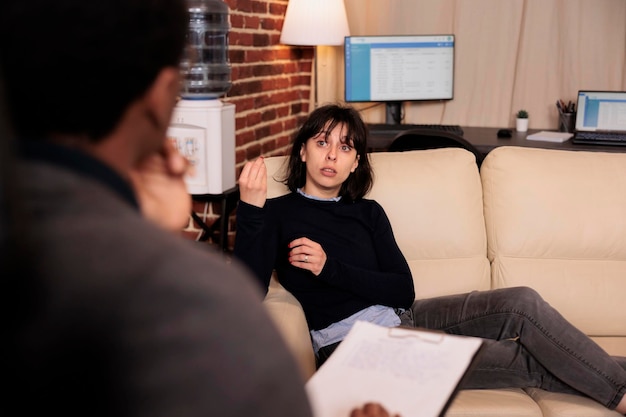 Malheureuse femme allongée sur un canapé lors d'une séance de psychothérapie avec un thérapeute, parlant de stress et de problèmes. Recevoir le soutien et l'aide d'un conseiller professionnel, des conseils de comportement.