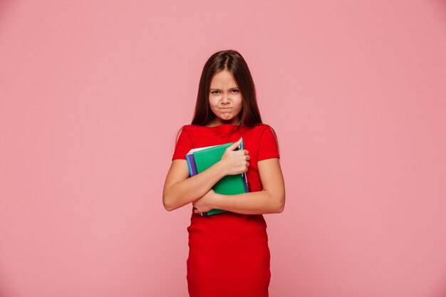 Malheureuse fille mécontente en robe rouge tenant le livre et à la recherche