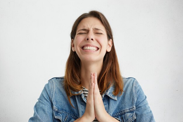 Malheureuse jeune femme stressée priant Dieu, implorant quelque chose avec avidité.
