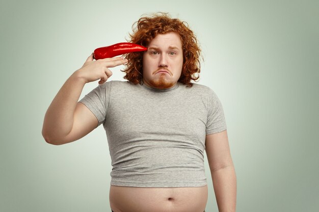 Malheureux déprimé rousse en surpoids dodu mâle portant un t-shirt trop petit avec son ventre qui sort