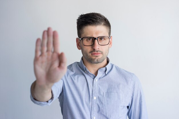 Malheureux insatisfait jeune homme avec chaume montrant le signe de rejet et en regardant la caméra.