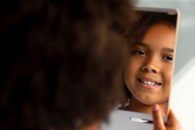 Photo gratuite maman aidant son enfant à coiffer les cheveux afro