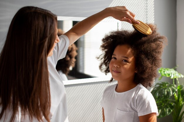 Maman aidant son enfant à coiffer les cheveux afro