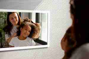 Photo gratuite maman aidant son enfant à coiffer les cheveux afro