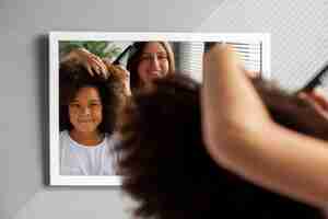 Photo gratuite maman aidant son enfant à coiffer les cheveux afro