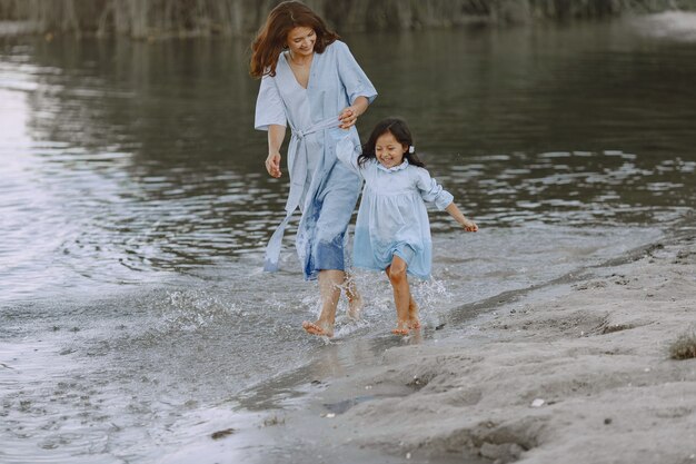 Maman et fille dans des robes identiques. Famille jouant au bord de la rivière.