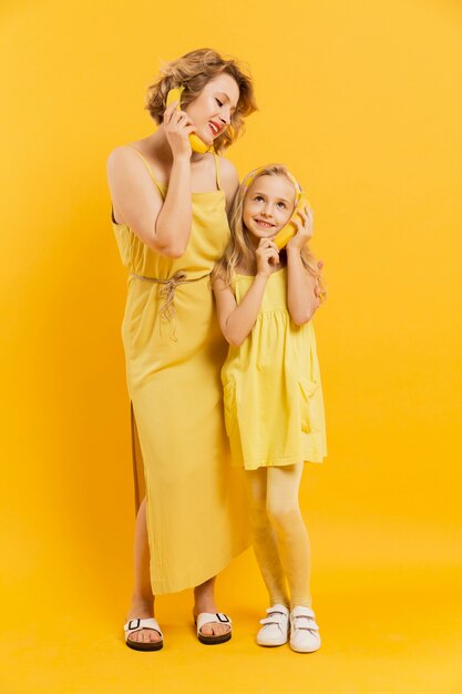 Maman et fille utilisant des bananes comme téléphone
