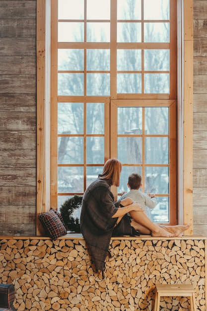 Photo gratuite maman et fils assis sur le rebord de la fenêtre et jouant.