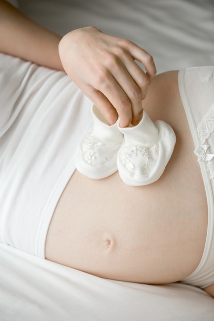 Photo gratuite maman future jouant avec des bottillons pour nouveau-né