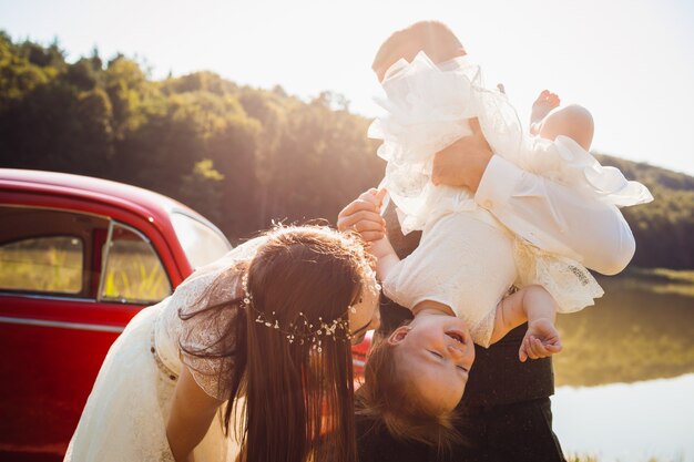 Maman joue avec sa petite fille pendant que papa la tient dans ses bras