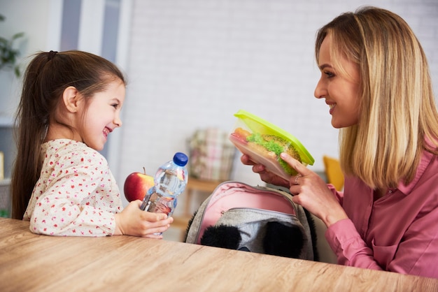 Maman Mettant Une Boîte à Lunch Avec Des Aliments Sains Dans Un Sac à Dos