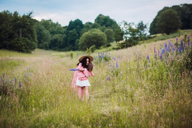 Maman et sa fille en robes roses courent pieds nus sur le terrain