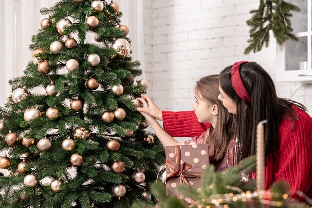 Maman et sa petite fille décorent ensemble le sapin de Noël