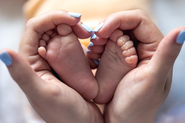 Photo gratuite maman tient les jambes d'un nouveau-né dans ses mains