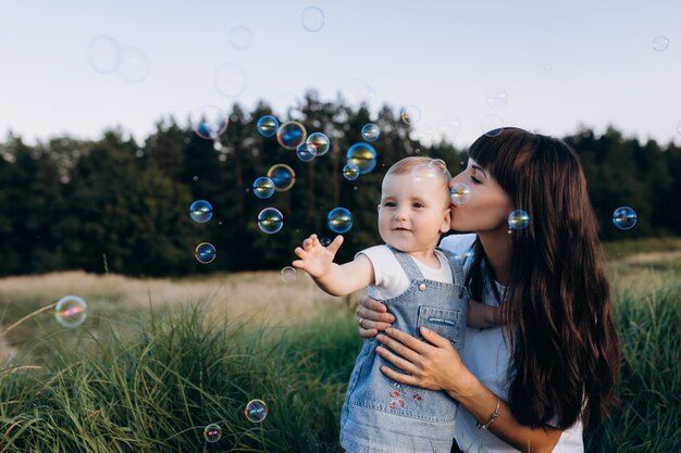 Maman tient sa fille dans ses bras pendant que des ballons de savon volent autour d&#39;eux