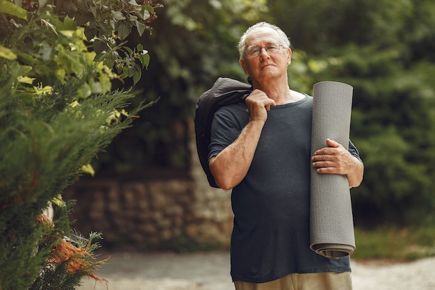 Man au parc d'été. Grangfather avec un tapis.