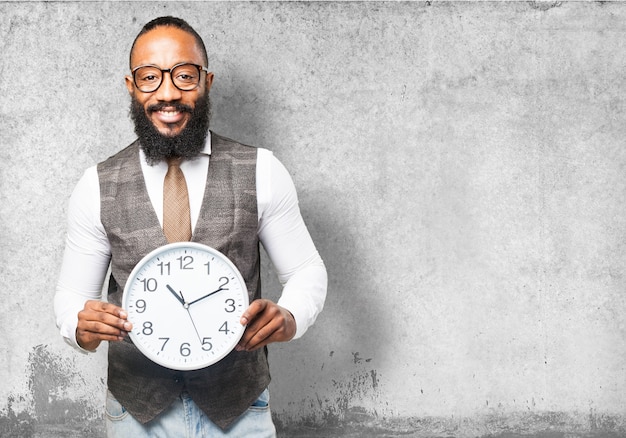 Man avec cravate souriant et tenant une horloge