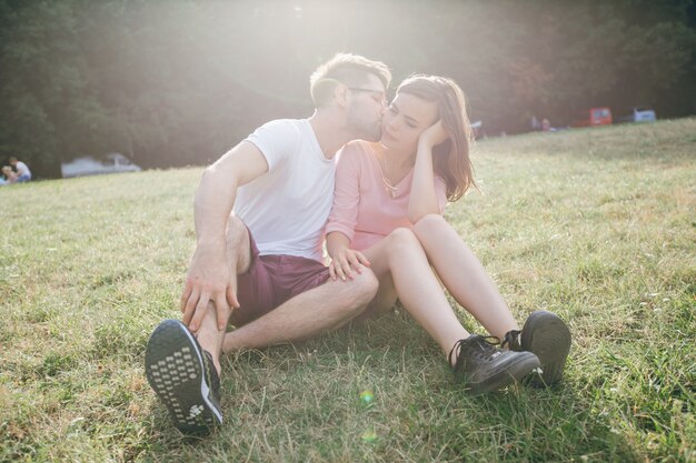 Man embrasser son partenaire assis sur la pelouse