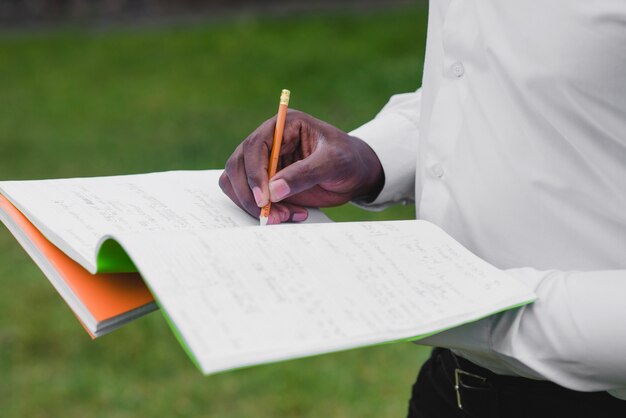 Man holding notebooks writing